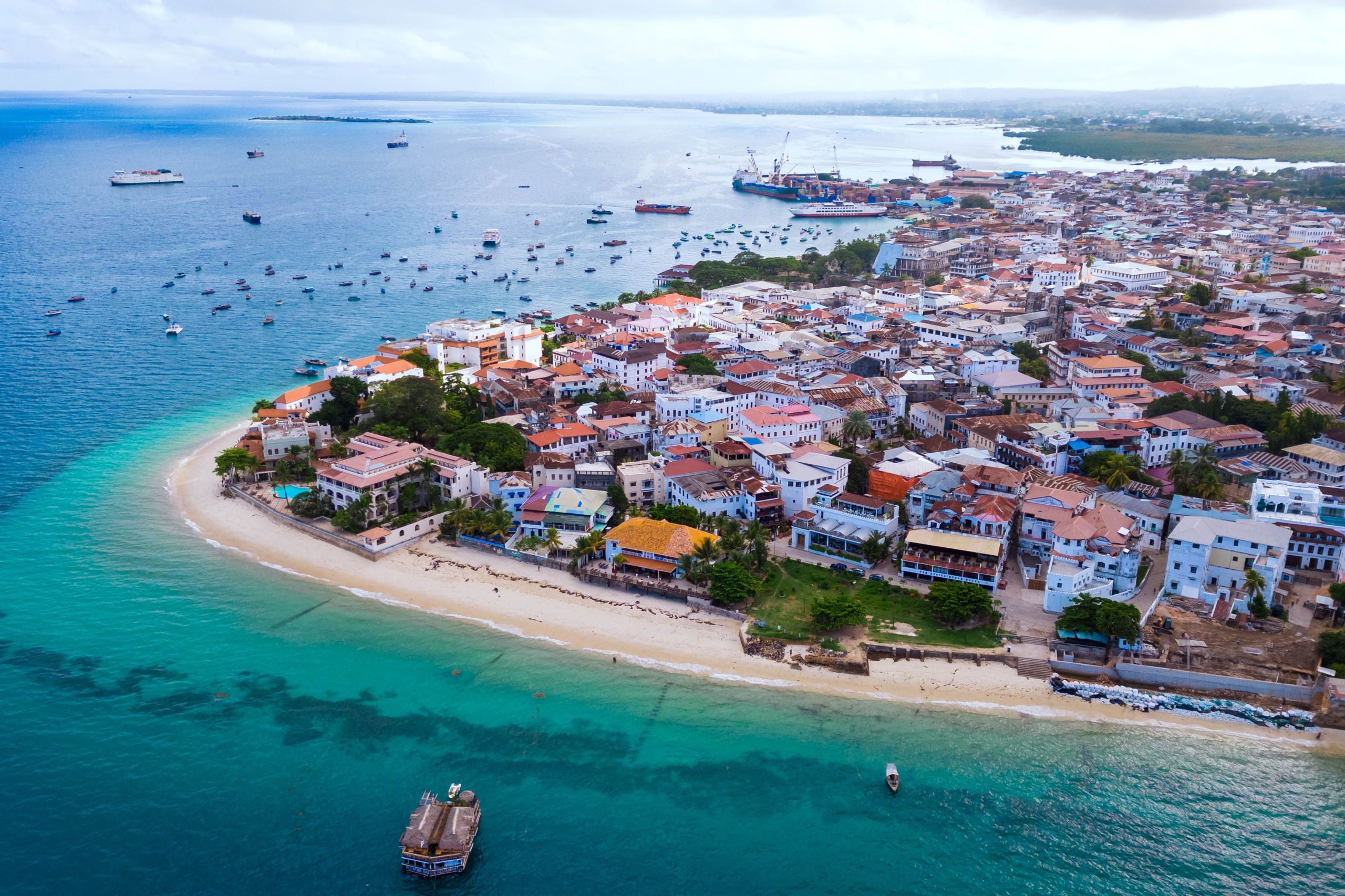 Aerial view of beautiful hotel in Indian ocean at sunset in summer. Zanzibar, Africa. Top view. Landscape with wooden hotel on the sea, azure water, sandy beach, green trees, buildings. Luxury resort